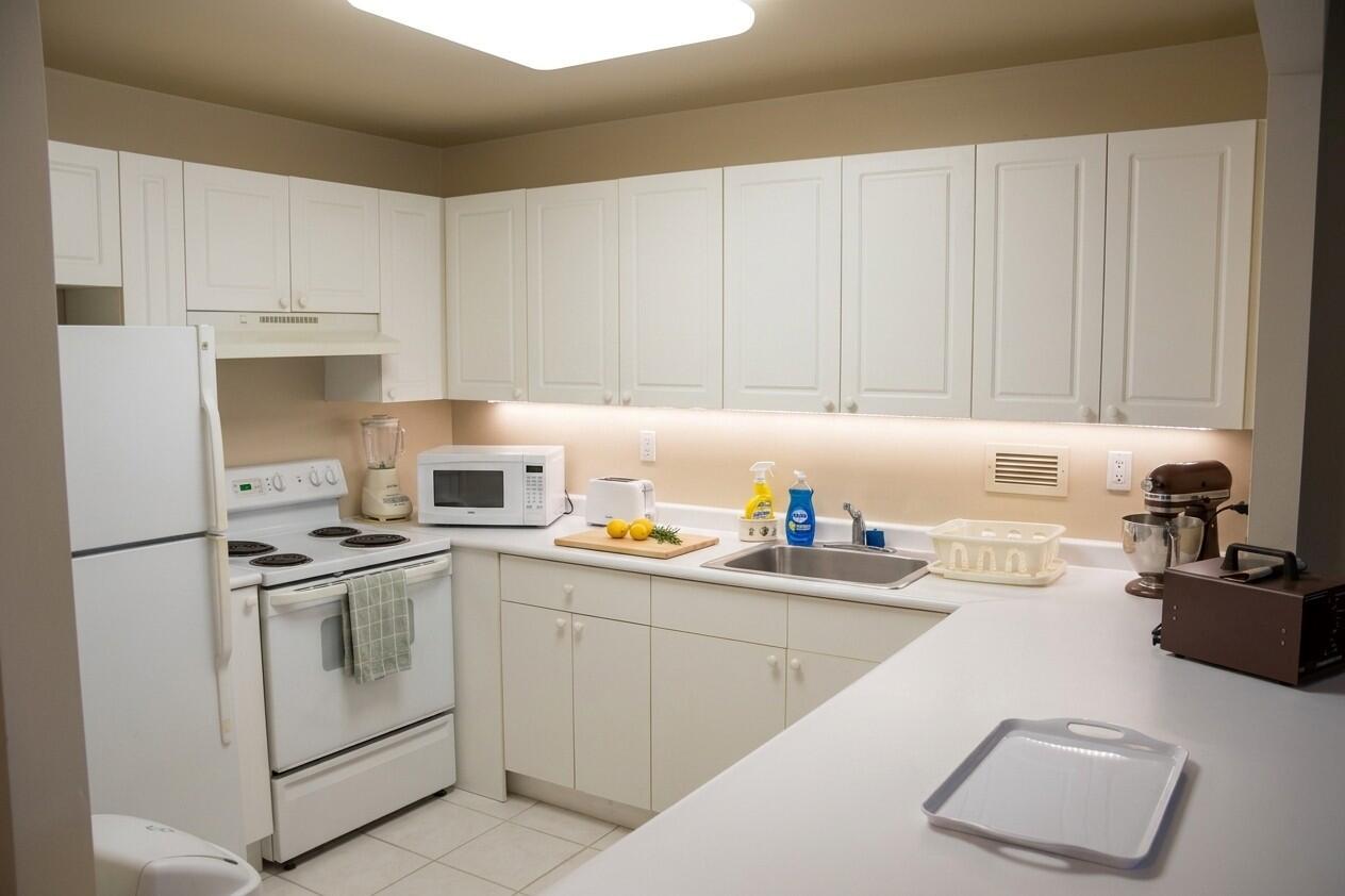 A kitchen features white cabinets, white appliances, a stainless steel sink, and light-colored countertops — 2301 Collins Avenue # 336, Miami Beach FL 33139, MIAMI BEACH, FL