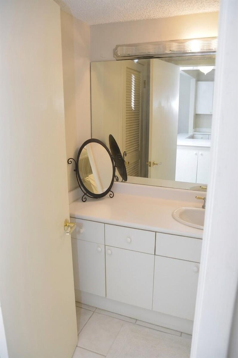 A bathroom vanity with a white countertop, sink, and a small decorative mirror — 2301 Collins Avenue # 336, Miami Beach FL 33139, MIAMI BEACH, FL