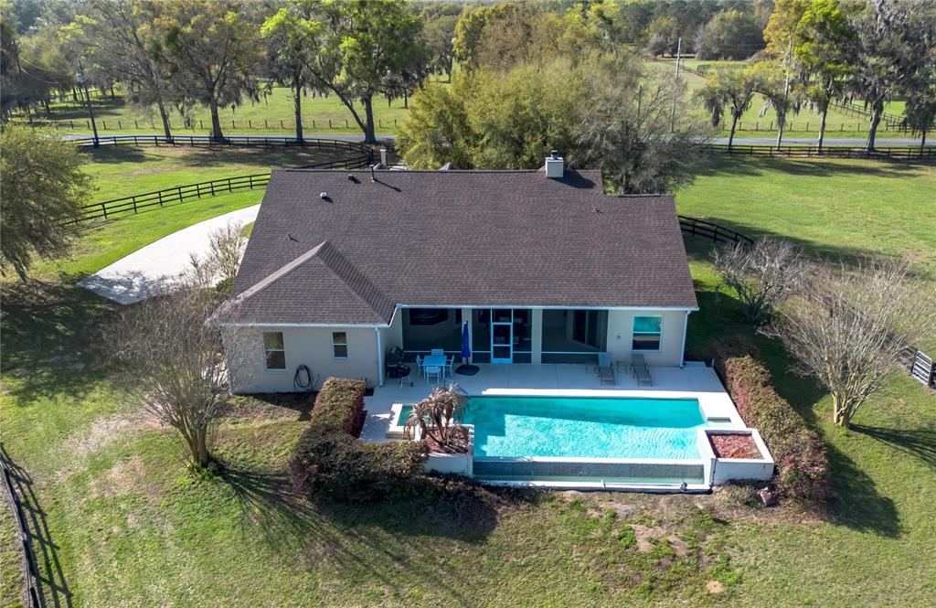 An aerial view shows a house with a swimming pool and patio in a rural setting — 8785 NW 63RD STREET, OCALA, FL