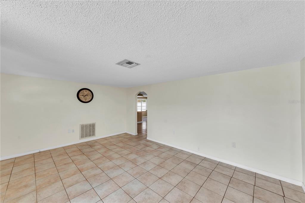 An empty room with beige tile flooring, white walls, and an arched doorway — 3401 SUPREME DRIVE, HOLIDAY, FL