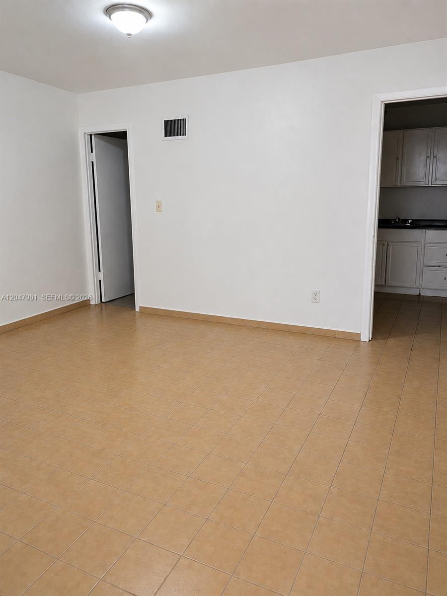 An empty room with white walls, beige tile flooring, and two doorways leading to other areas — 5810 W Flagler St # 3, Miami FL 33144, MIAMI, FL