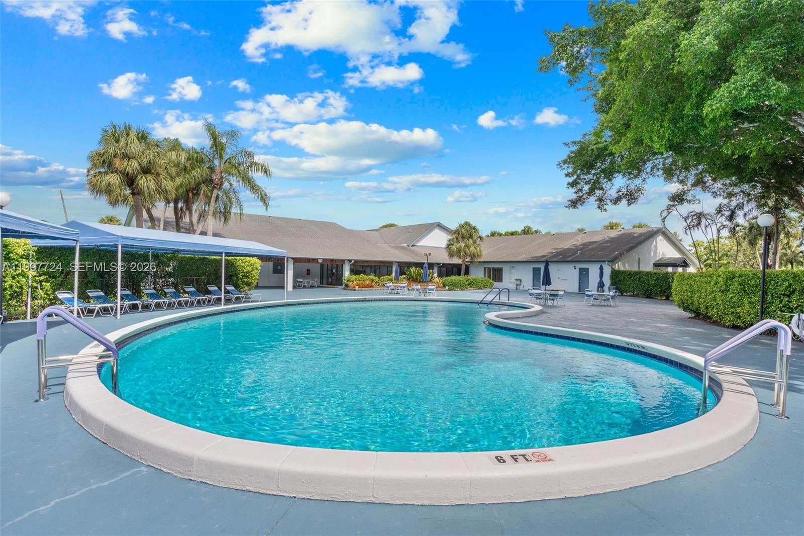 A kidney-shaped swimming pool sits on a concrete deck in front of a building — 1480 NW 80th Ave # 304, Margate FL 33063, MARGATE, FL