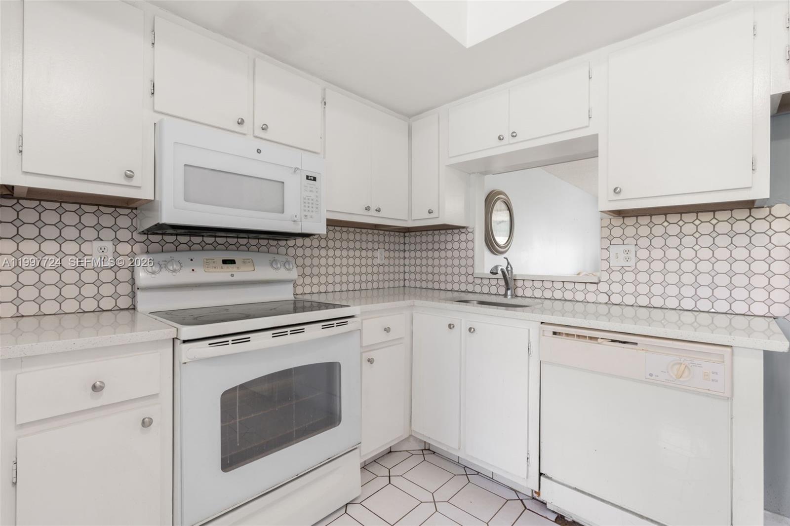 A kitchen features white cabinetry, a white electric stove, a dishwasher, and hexagonal tile backsplash — 1480 NW 80th Ave # 304, Margate FL 33063, MARGATE, FL