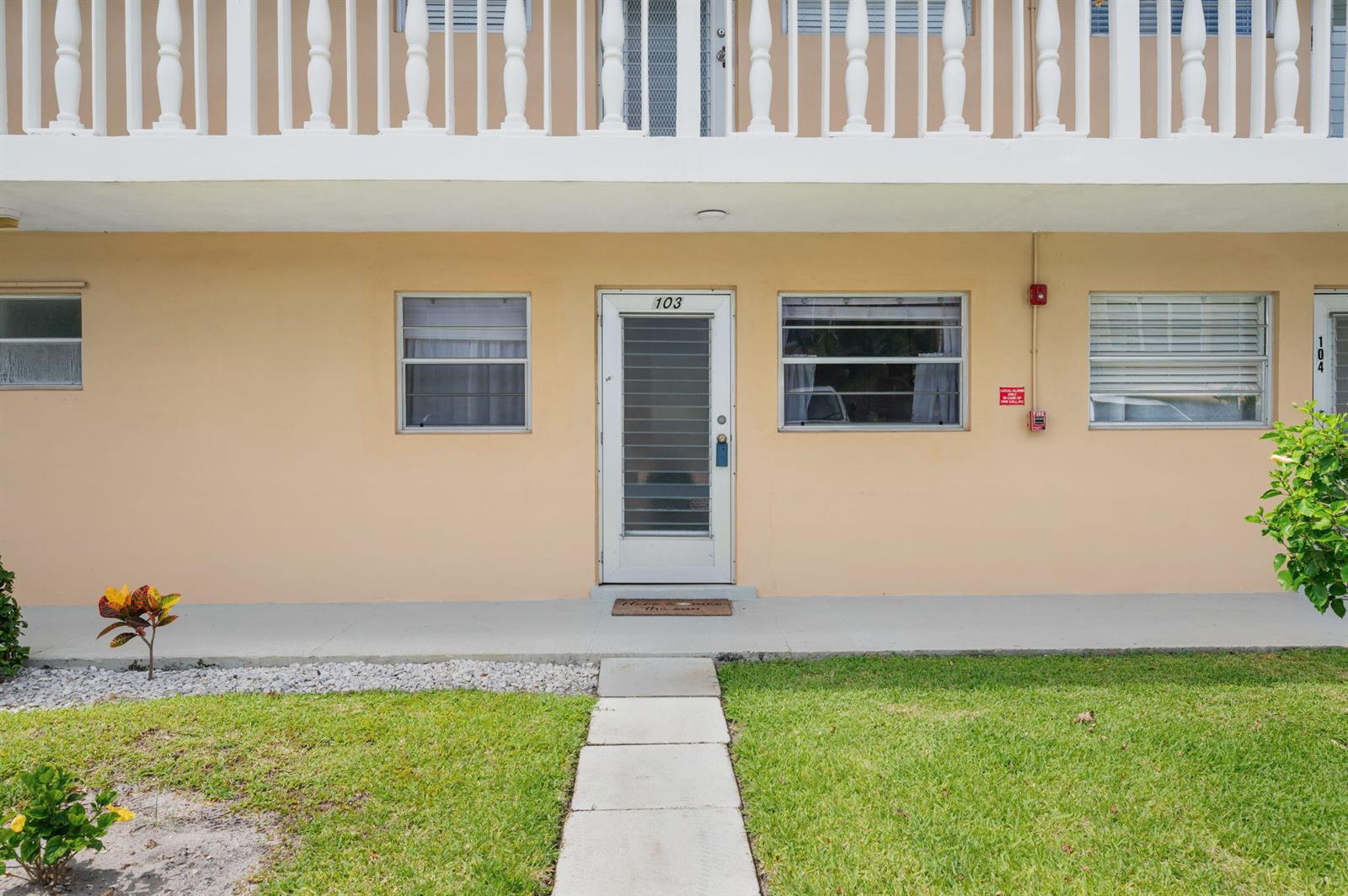 The exterior view shows a ground-level apartment entrance with a white door labeled 103 — 2102 NE 1st Way # 103, Boynton Beach FL 33435, BOYNTON BEACH, FL