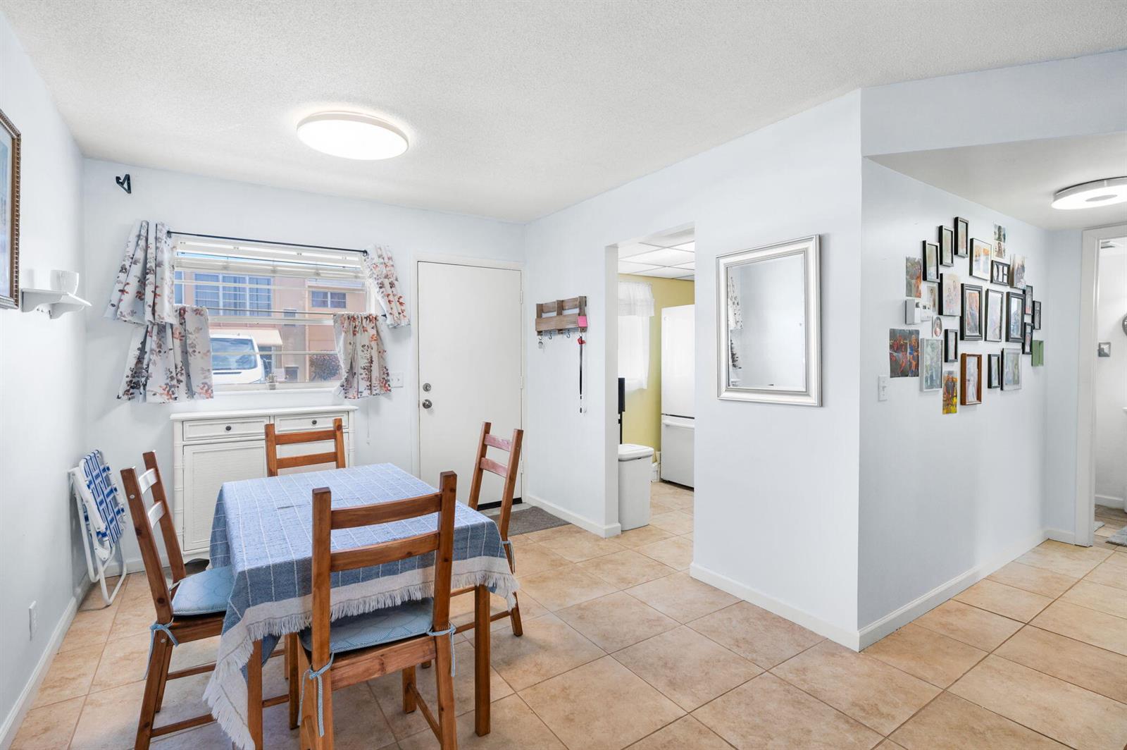 A dining area with a table, chairs, tile flooring, and a gallery wall of photos — 2102 NE 1st Way # 103, Boynton Beach FL 33435, BOYNTON BEACH, FL
