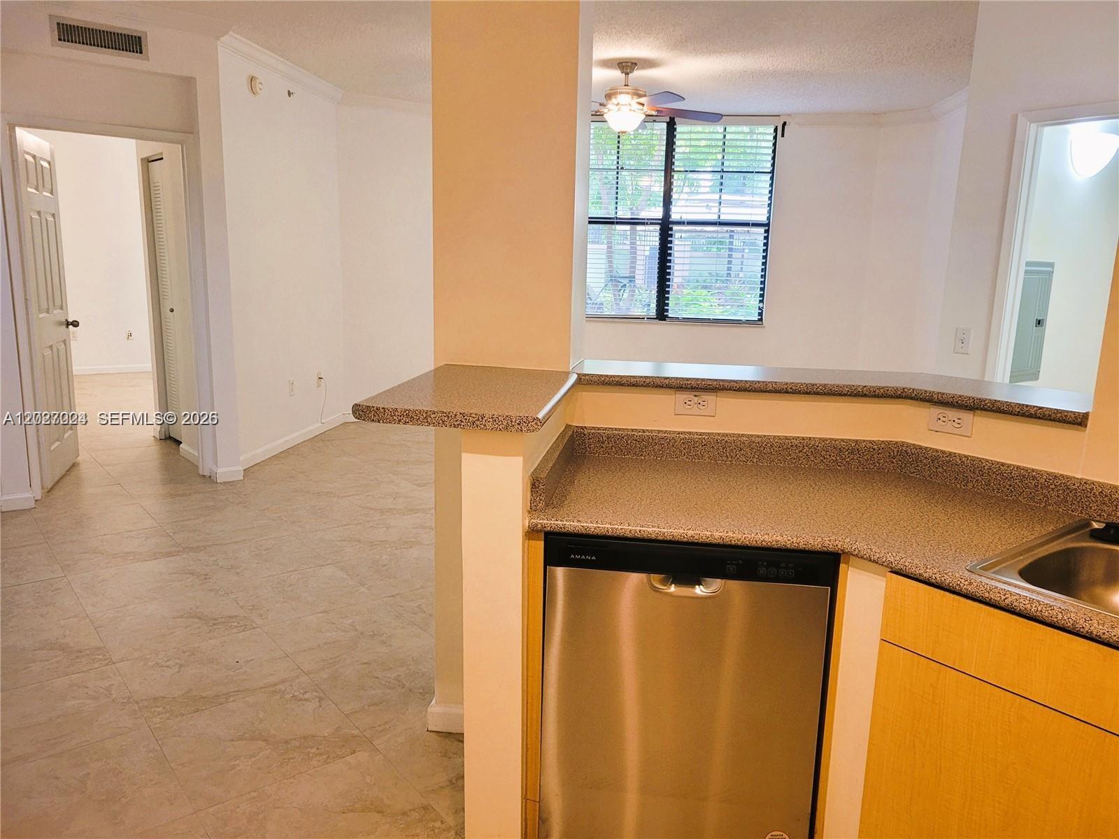 A kitchen with a stainless steel dishwasher and speckled countertops overlooks an adjacent living area — 1919 Van Buren St # 111A, Hollywood FL 33020, HOLLYWOOD, FL