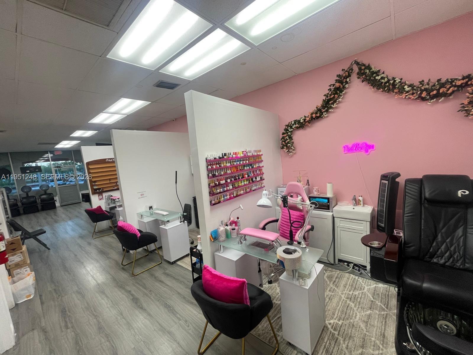 A nail salon features multiple workstations with pink accents, white partitions, and wood-look flooring — 627 S State Road 7, Hollywood FL 33023, HOLLYWOOD, FL