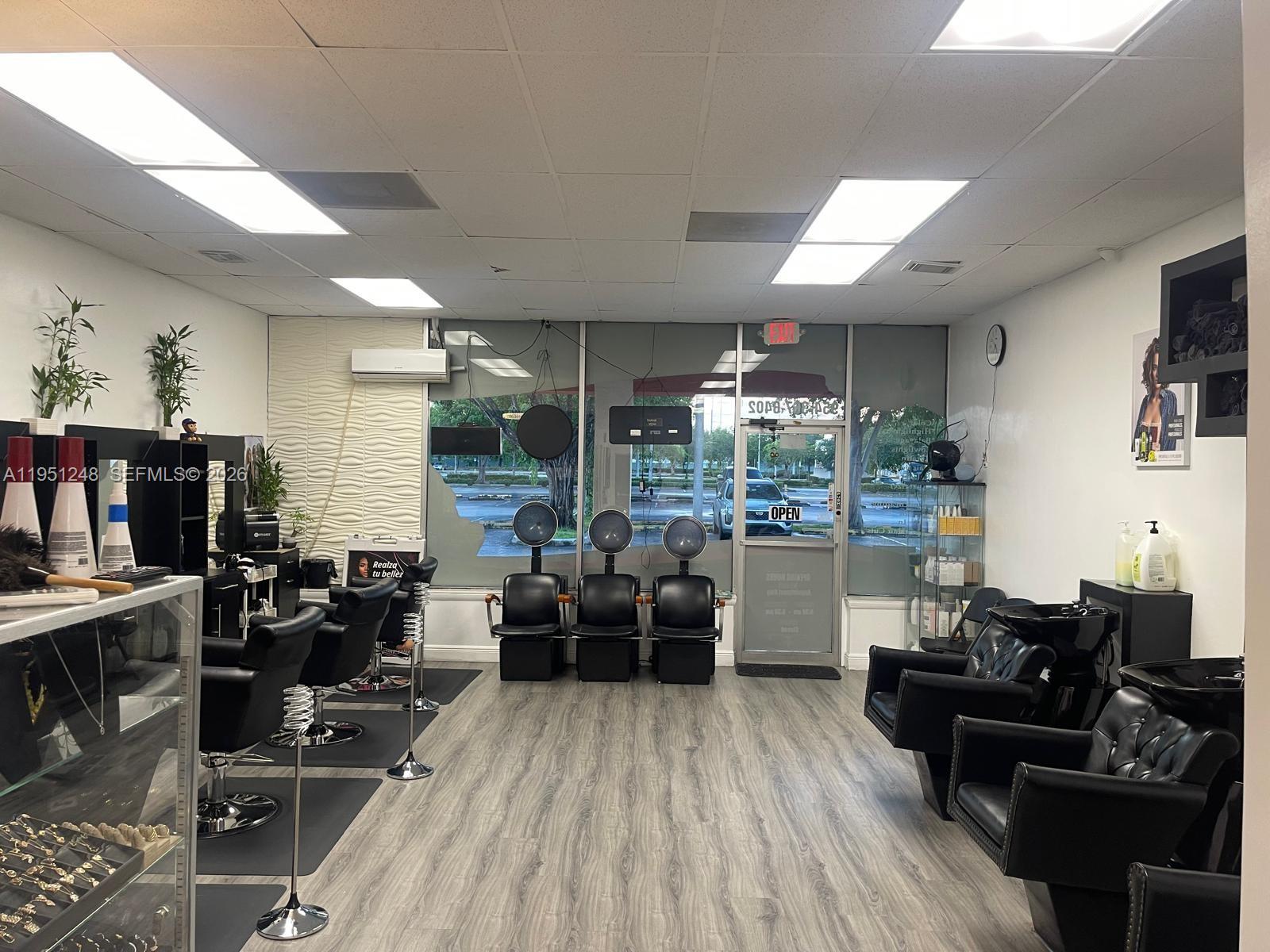A hair salon features black styling chairs, hooded dryers, shampoo stations, and wood-look flooring — 627 S State Road 7, Hollywood FL 33023, HOLLYWOOD, FL