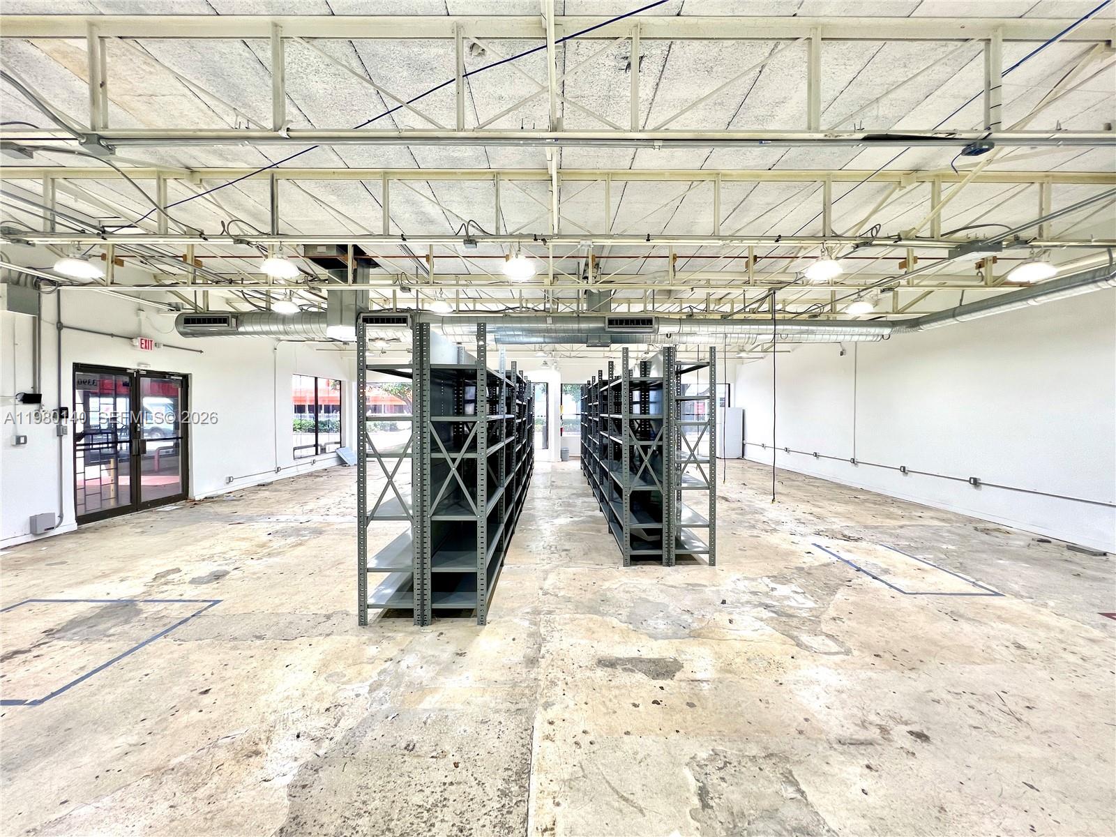 An industrial warehouse space features exposed ceiling trusses, concrete floors, and two rows of metal shelving — 3390 SW Coral Way, Miami FL 33142, MIAMI, FL