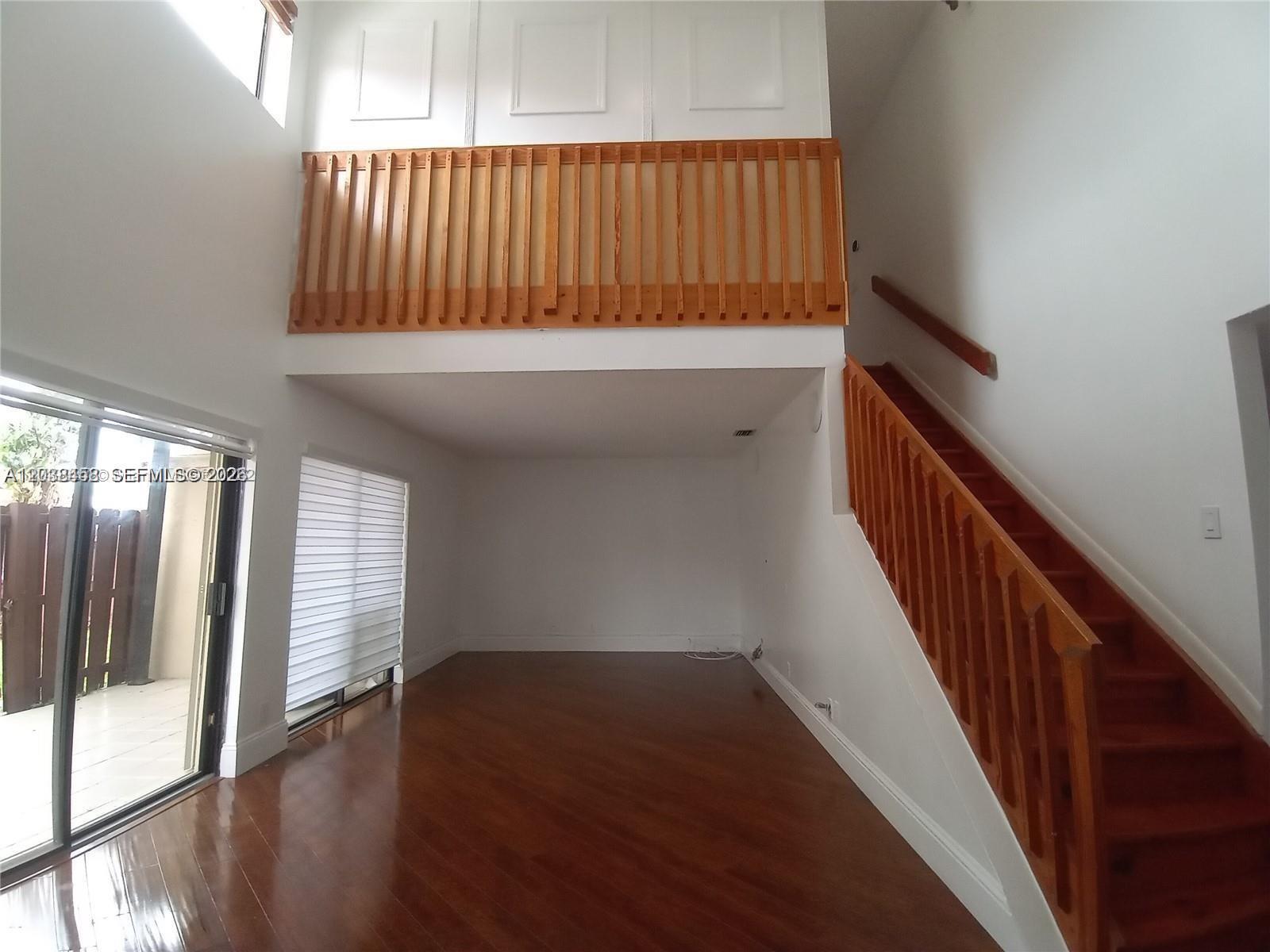 A living room features dark wood flooring, a wooden staircase, and a lofted balcony area — 6533 NW 170th Ln, Hialeah FL 33015, HIALEAH, FL