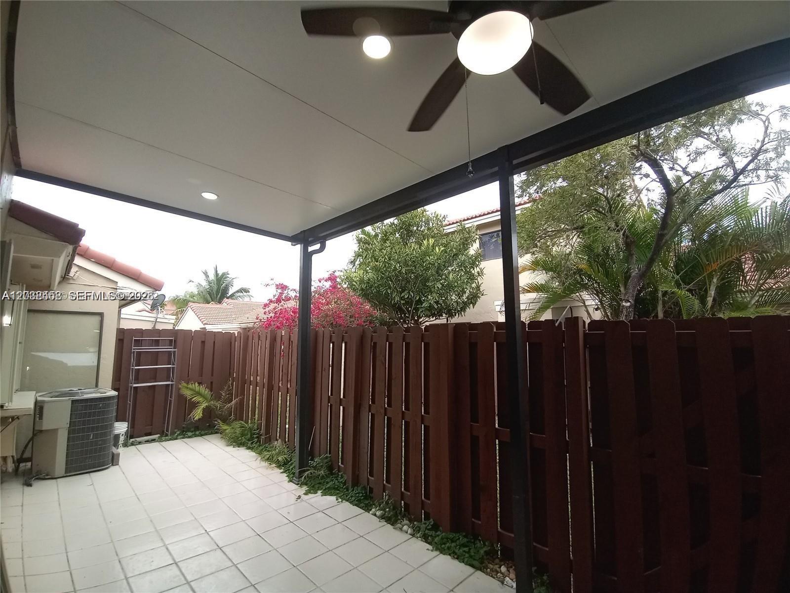 A covered patio features a ceiling fan, tiled flooring, and a wooden privacy fence — 6533 NW 170th Ln, Hialeah FL 33015, HIALEAH, FL