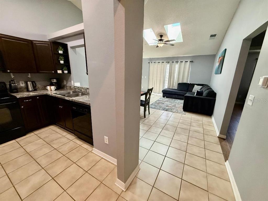 A kitchen with dark cabinets and tile flooring opens into a living area with skylights — 142 GLASGOW COURT, DAVENPORT, FL