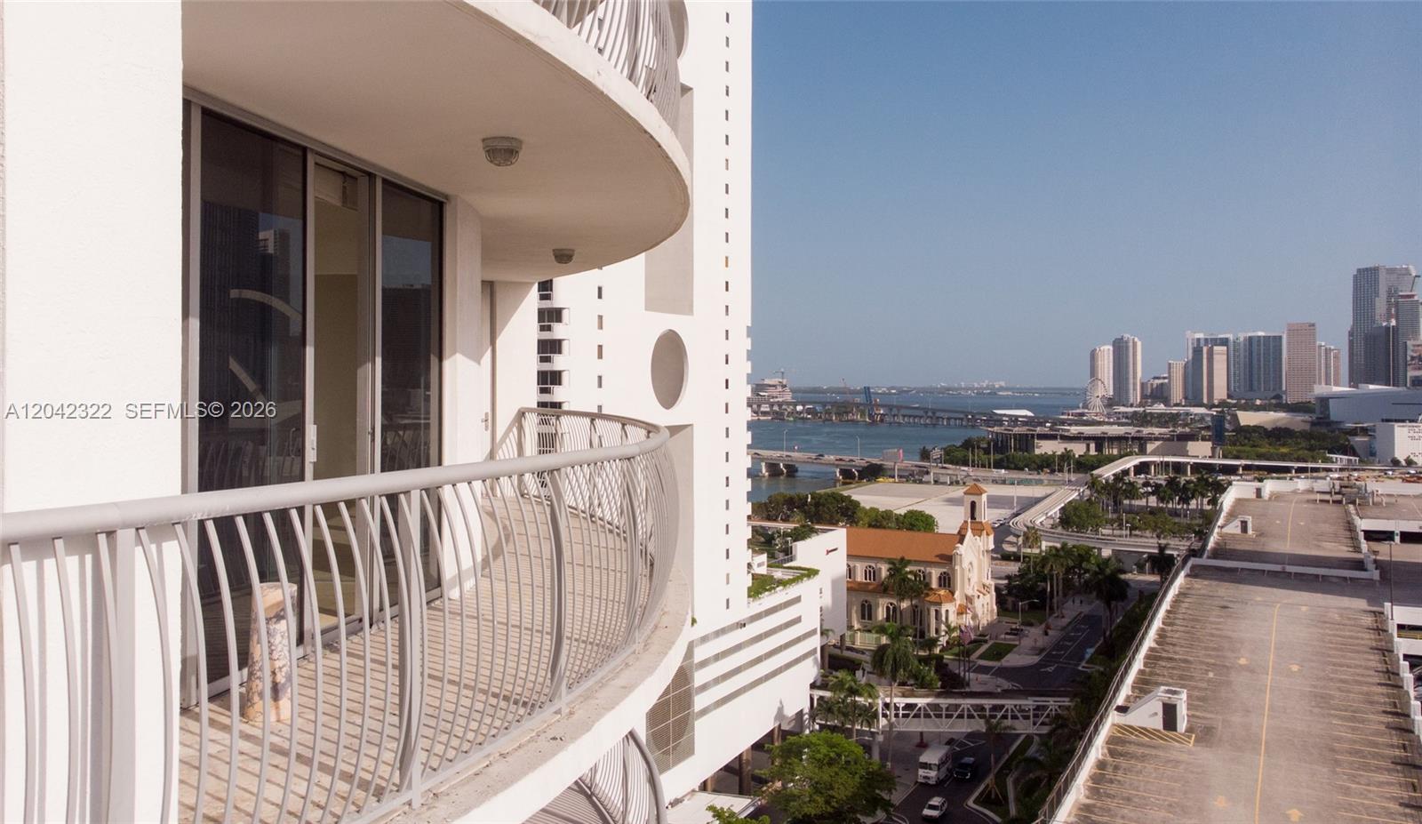A high-rise balcony overlooks a city skyline, a bridge, and a nearby church — 1750 N Bayshore Dr # 1814, Miami FL 33132, MIAMI, FL