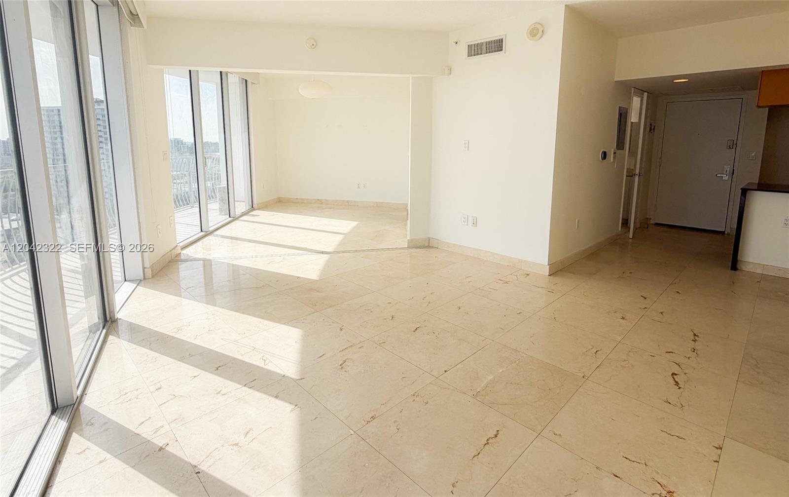 An empty living area features light-colored tile flooring, white walls, and floor-to-ceiling glass balcony doors — 1750 N Bayshore Dr # 1814, Miami FL 33132, MIAMI, FL