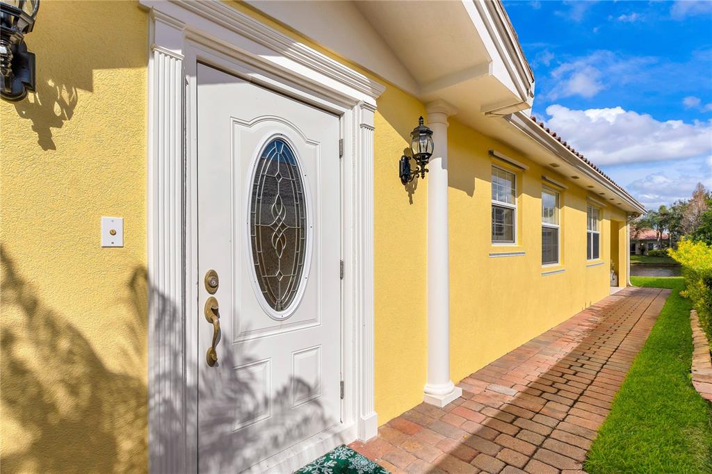 A yellow house exterior features a white front door with an oval glass insert — 11831 FAN TAIL LANE, ORLANDO, FL