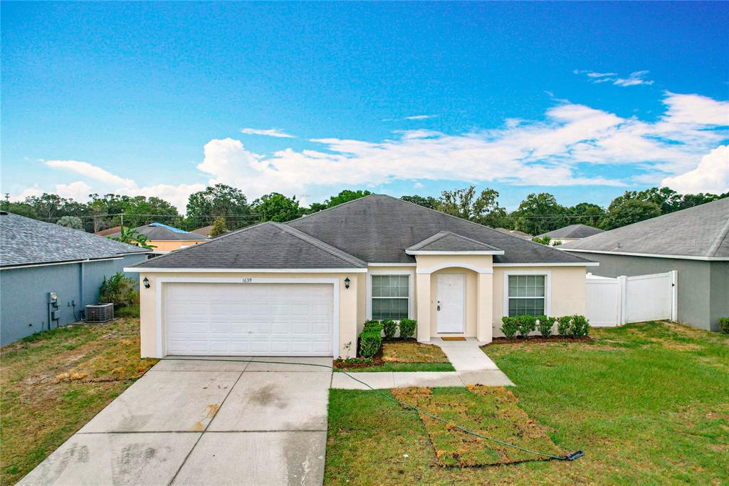 A single-story house with a beige exterior, a two-car garage, and a concrete driveway — 1639 SADDLEHORN DRIVE, LAKELAND, FL