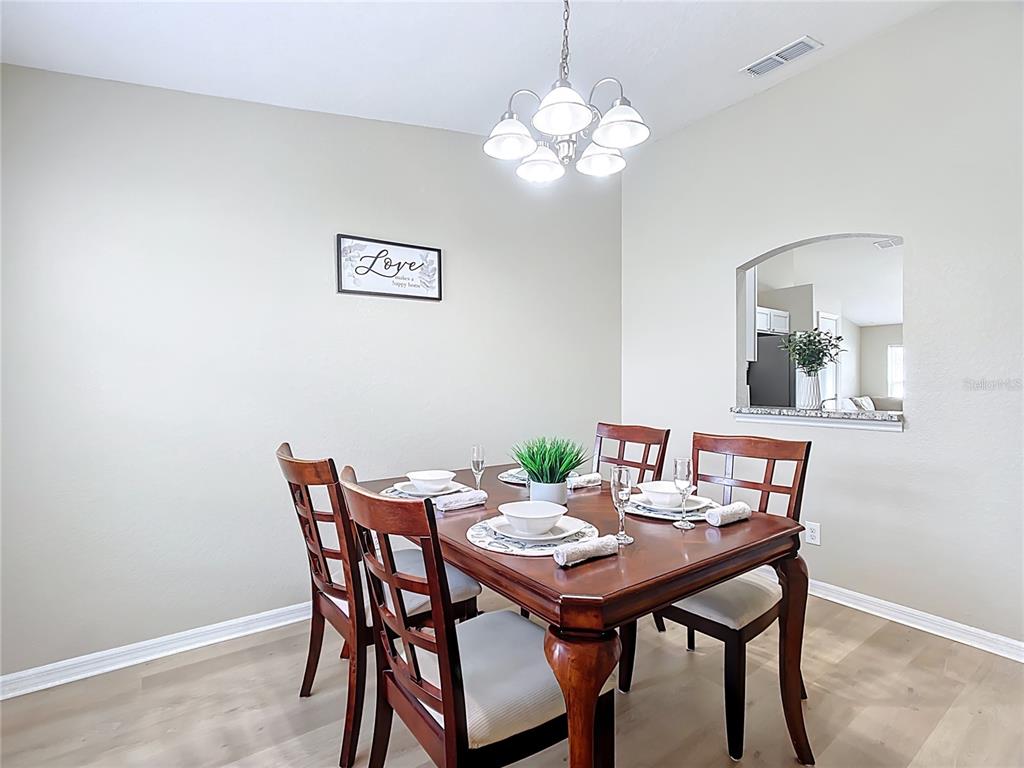 A dining room features a wooden table with four chairs, a chandelier, and wall decor — 1639 SADDLEHORN DRIVE, LAKELAND, FL