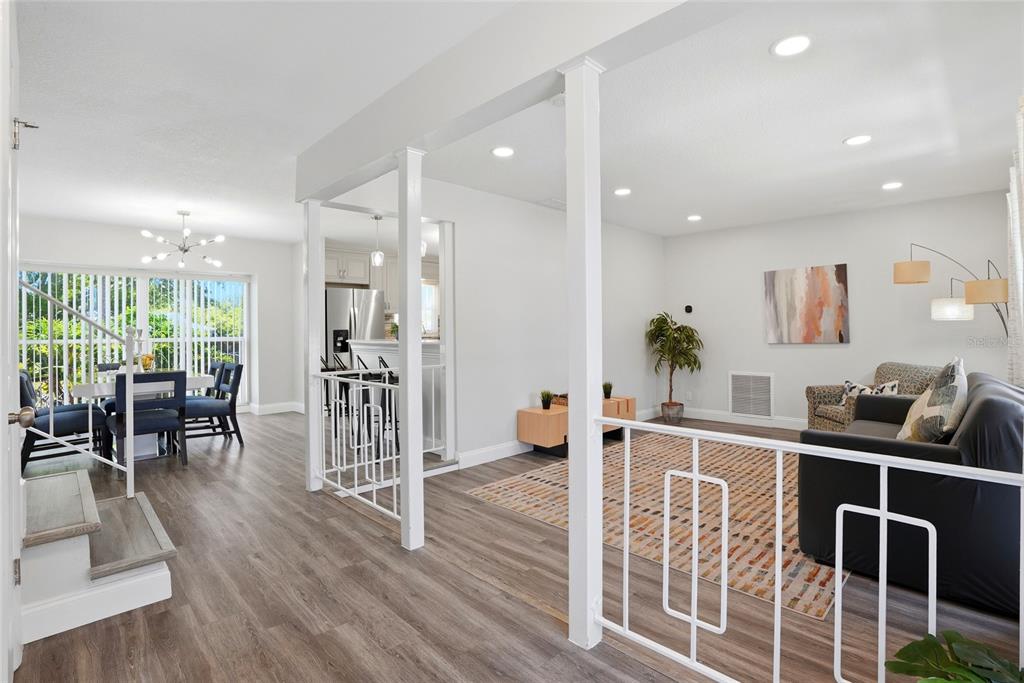 A living room and dining area feature white railings, light wood flooring, and recessed lighting — 721 VILLAGE PLACE, BRANDON, FL