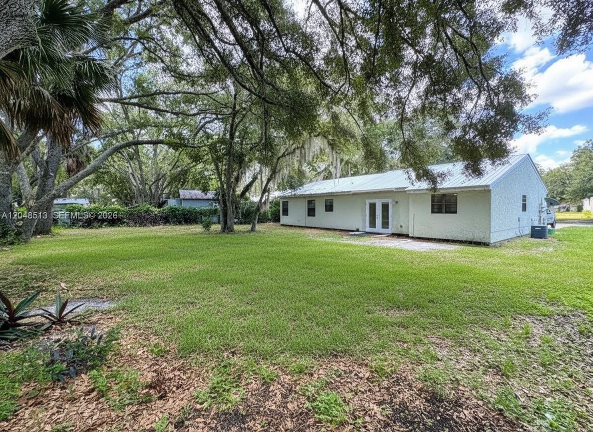 The exterior of a single-story house with a metal roof sits on a grassy lot — 4005 E Sunflower Cir, La Belle FL 33935, LA BELLE, FL