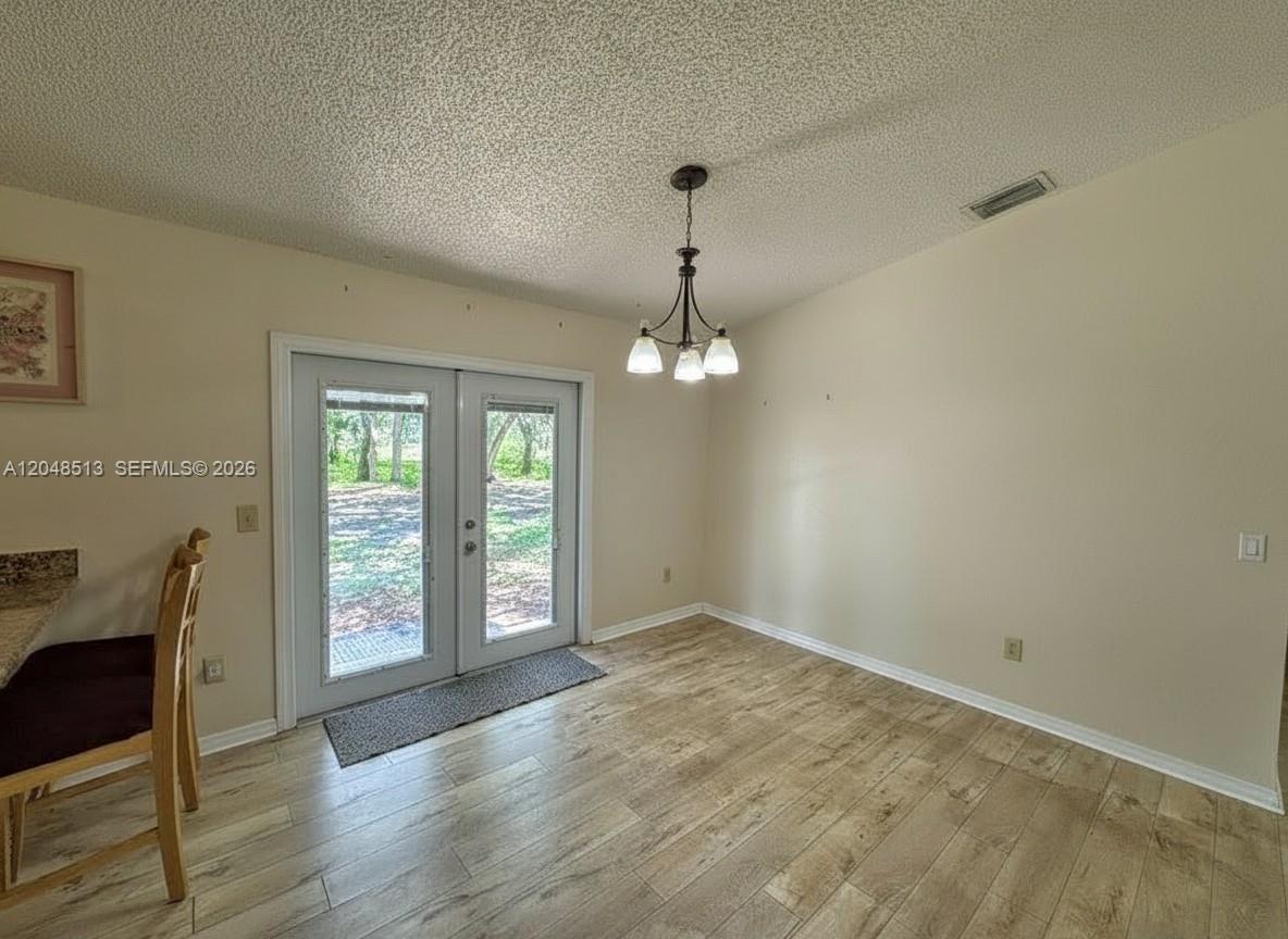 A dining area features light wood-look flooring, a chandelier, and French doors leading outside — 4005 E Sunflower Cir, La Belle FL 33935, LA BELLE, FL