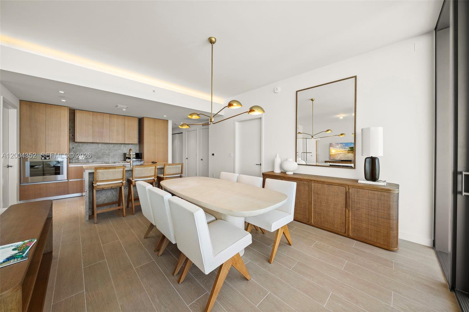 A dining area features a light wood table, white chairs, and a wooden sideboard — 500 Alton Rd # 1707, Miami Beach FL 33139, MIAMI BEACH, FL