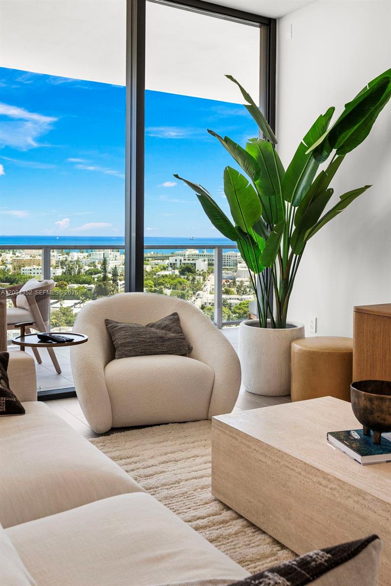 A modern living room features a cream armchair, a large potted plant, and ocean views — 500 Alton Rd # 1707, Miami Beach FL 33139, MIAMI BEACH, FL