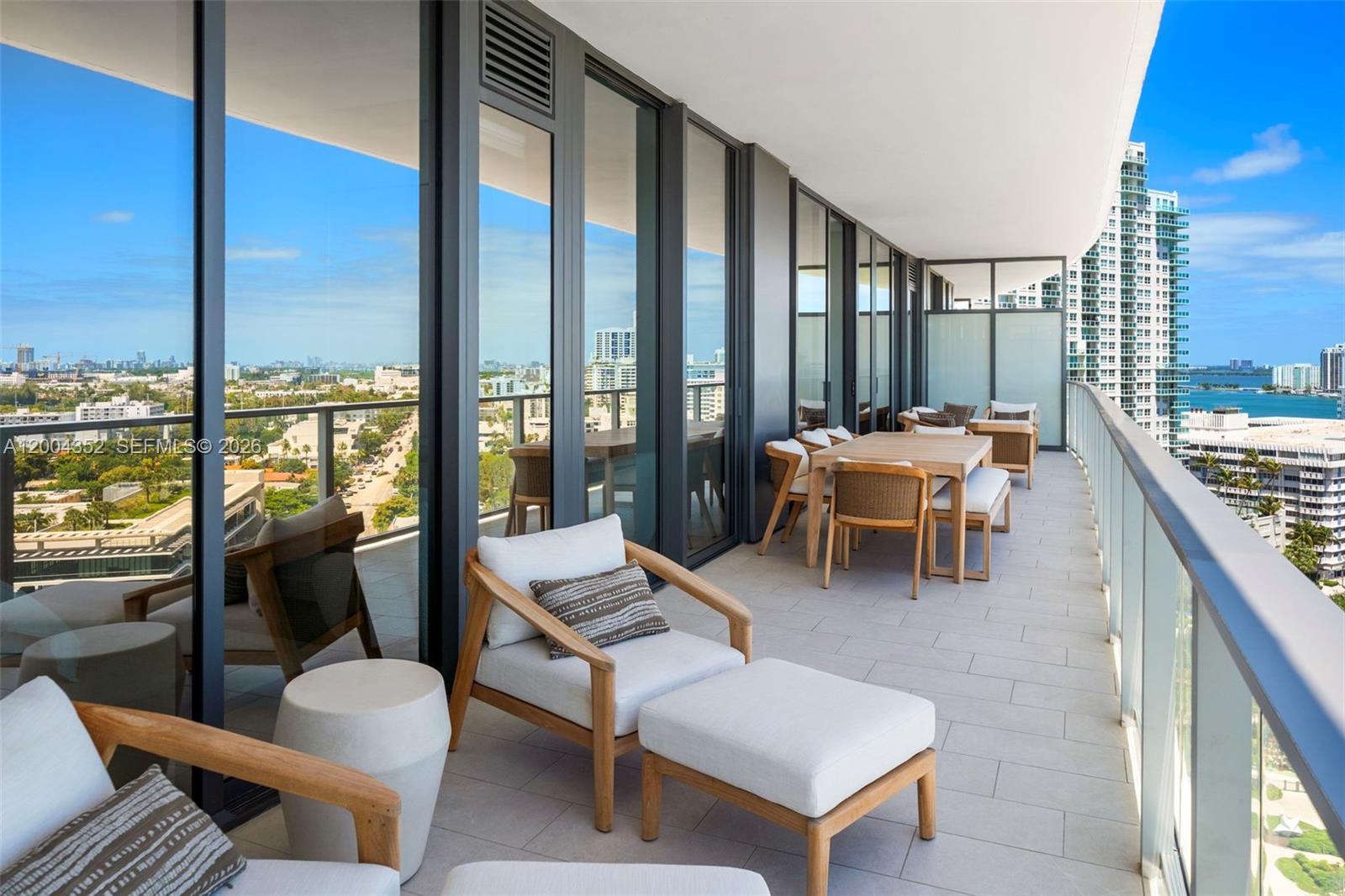 A spacious balcony with outdoor furniture overlooks a city skyline and a body of water — 500 Alton Rd # 1707, Miami Beach FL 33139, MIAMI BEACH, FL
