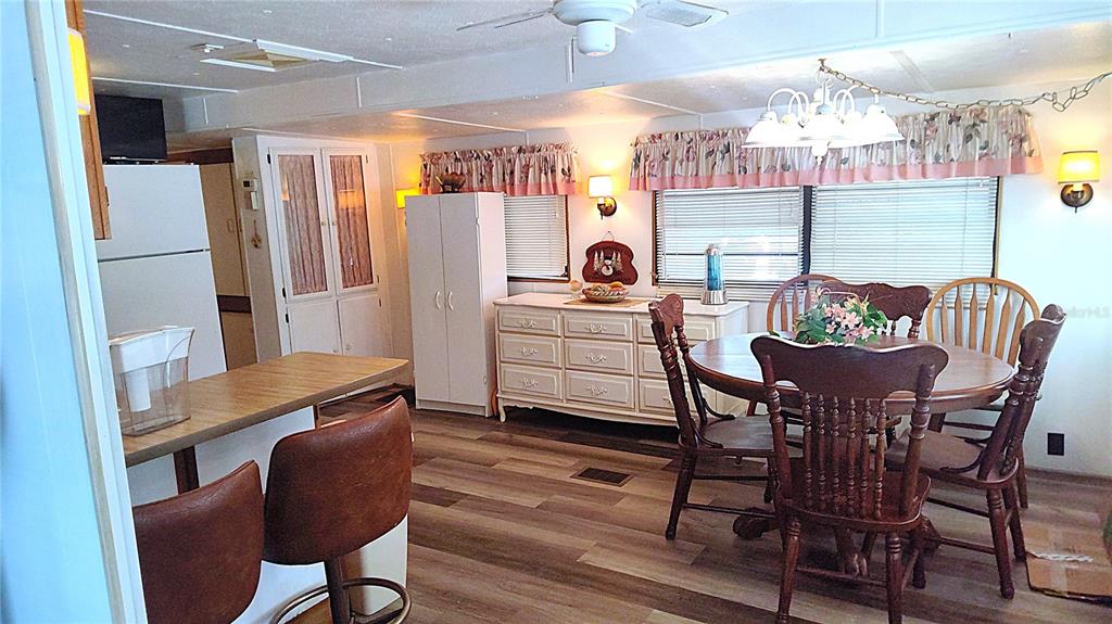 A dining area with wood-look flooring, a round table, and a white dresser — 3300 26TH AVENUE E UNIT 201, BRADENTON, FL