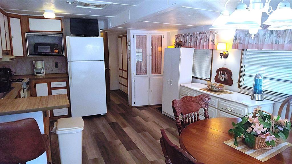 A kitchen and dining area with wood-look flooring, white cabinetry, and a round wooden table — 3300 26TH AVENUE E UNIT 201, BRADENTON, FL