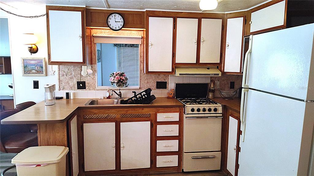 A kitchen features wood-trimmed white cabinets, a white stove, and a white refrigerator — 3300 26TH AVENUE E UNIT 201, BRADENTON, FL