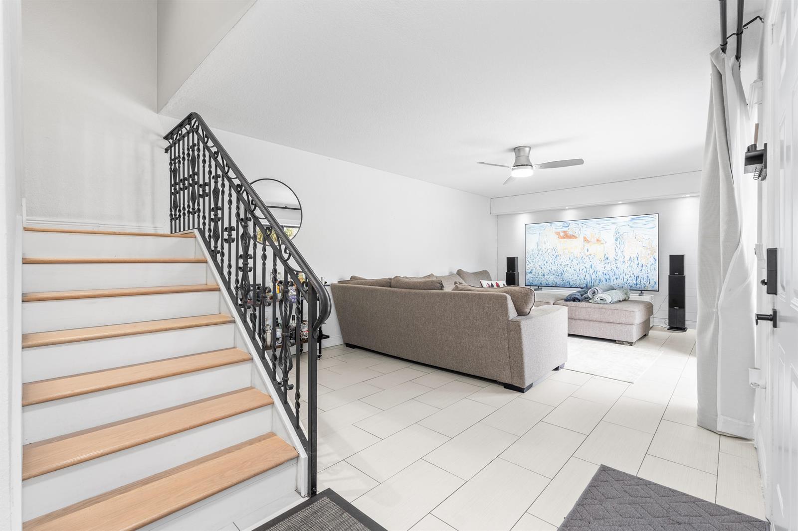 A living room features a staircase with a black iron railing and light tile flooring — 3611 36th Way, West Palm Beach FL 33407, WEST PALM BEACH, FL