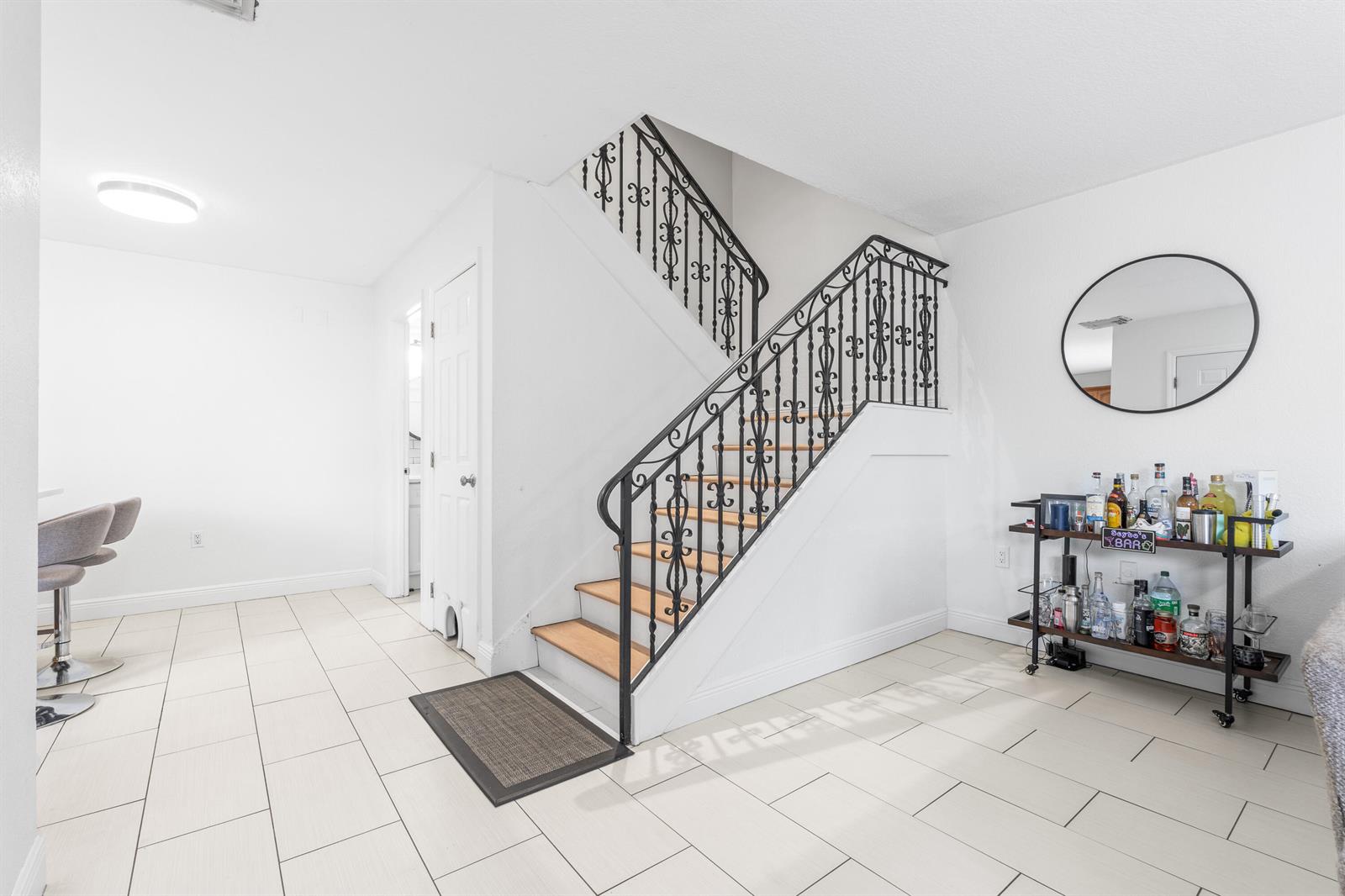 A room with white tile floors, a staircase with black iron railings, and a bar cart — 3611 36th Way, West Palm Beach FL 33407, WEST PALM BEACH, FL
