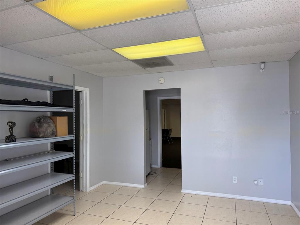 A room with gray walls, tile flooring, a drop ceiling, and metal shelving units — 10949 SW 93RD TERRACE UNIT 203, OCALA, FL