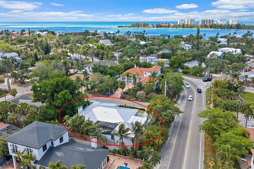 An aerial view shows a white house with a metal roof surrounded by lush trees — 3515 LA PALOMA AVENUE, SARASOTA, FL