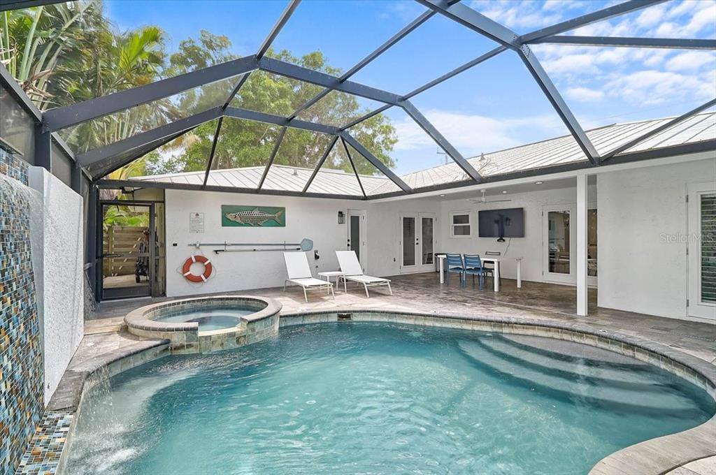 A screened-in patio features a swimming pool, a hot tub, and a tiled water feature — 3515 LA PALOMA AVENUE, SARASOTA, FL