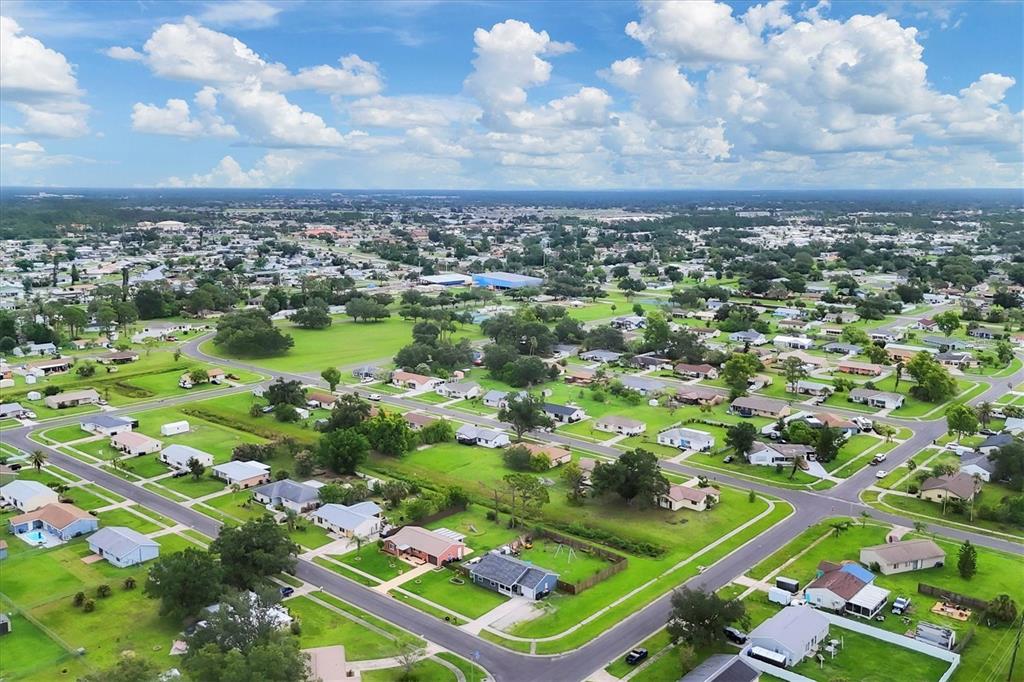 An aerial view of a suburban neighborhood with single-family homes, green lawns, and paved streets — 7590 LYNCREST STREET, NORTH PORT, FL