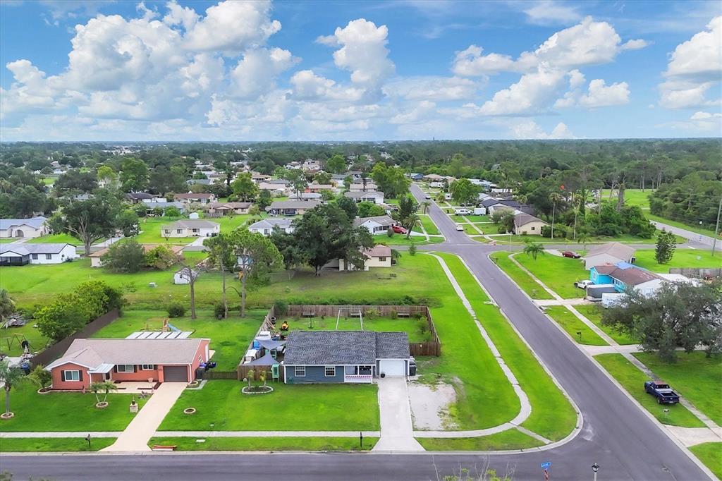 An aerial view shows a suburban neighborhood with single-story houses, green lawns, and paved streets — 7590 LYNCREST STREET, NORTH PORT, FL