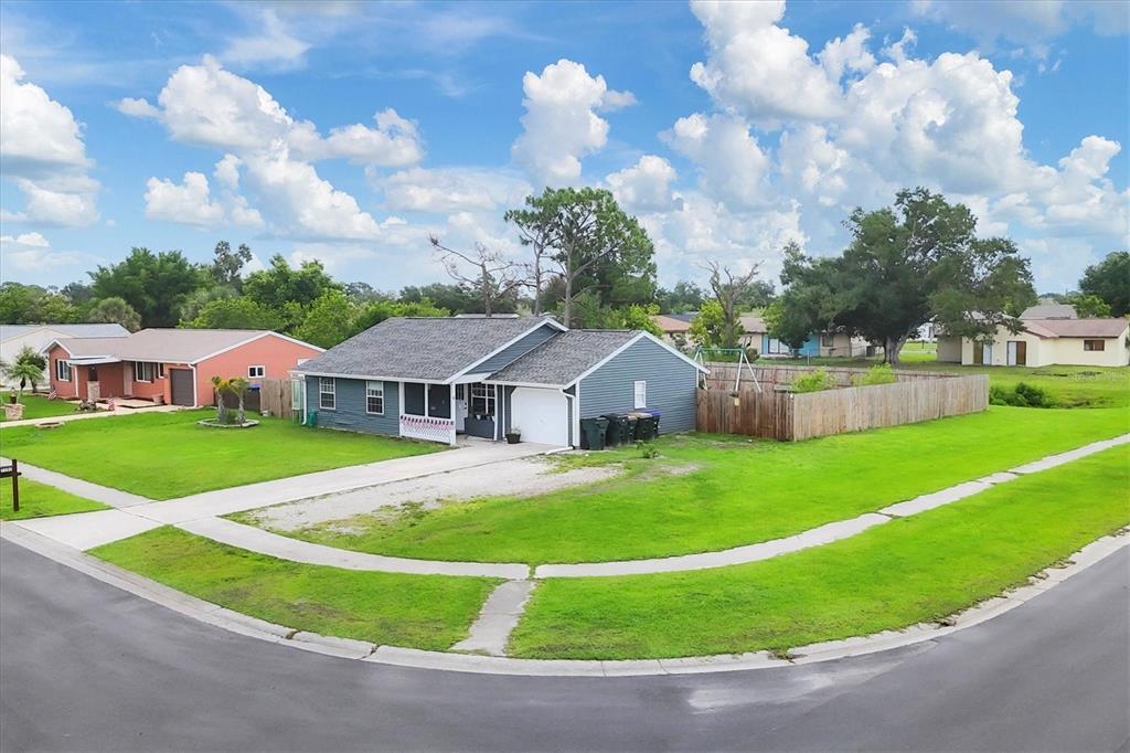 A blue single-story house with a white garage sits on a corner lot with grass — 7590 LYNCREST STREET, NORTH PORT, FL