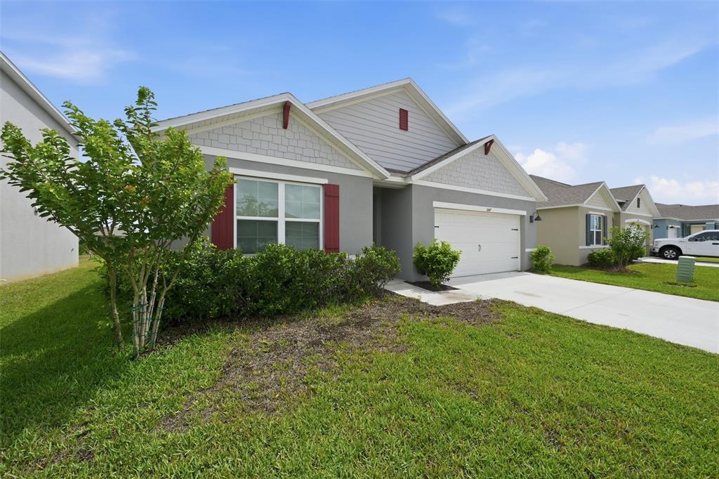 A gray single-story house with a white garage door, red shutters, and a front lawn — 2647 HOUSE FINCH ROAD, ST CLOUD, FL