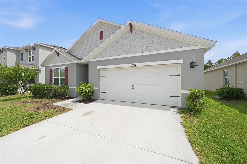 A gray single-story house with a white garage door and a concrete driveway — 2647 HOUSE FINCH ROAD, ST CLOUD, FL