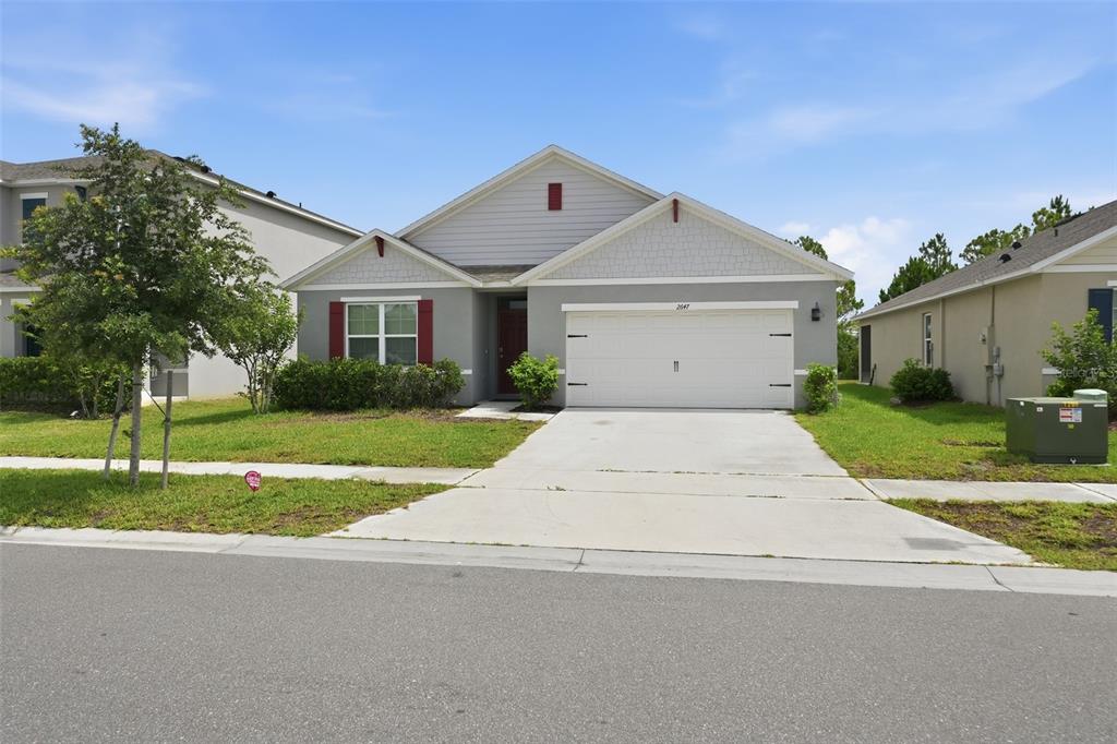 A single-story suburban house with a gray exterior, white garage door, and a front lawn — 2647 HOUSE FINCH ROAD, ST CLOUD, FL