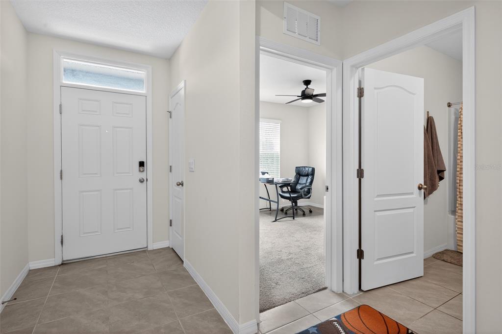 An entryway with tile flooring leads to a home office and a bathroom door — 2647 HOUSE FINCH ROAD, ST CLOUD, FL