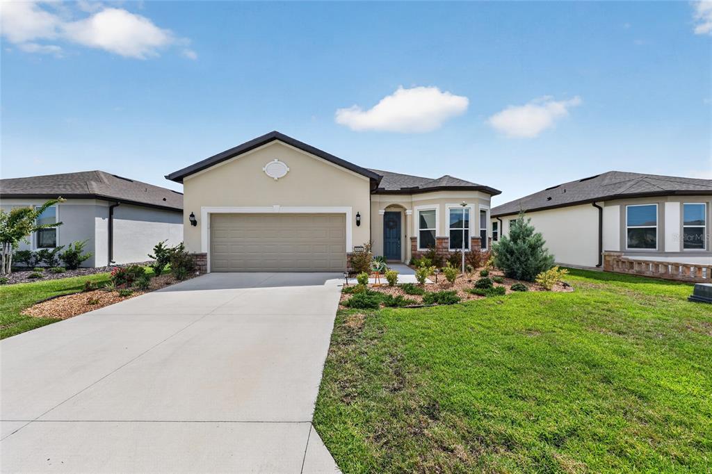 A single-story suburban house with a beige stucco exterior, a two-car garage, and a lawn — 8644 SW 59TH LANE ROAD, OCALA, FL