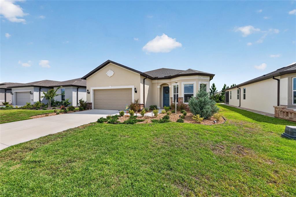 A single-story suburban house with a tan stucco exterior, a two-car garage, and landscaping — 8644 SW 59TH LANE ROAD, OCALA, FL