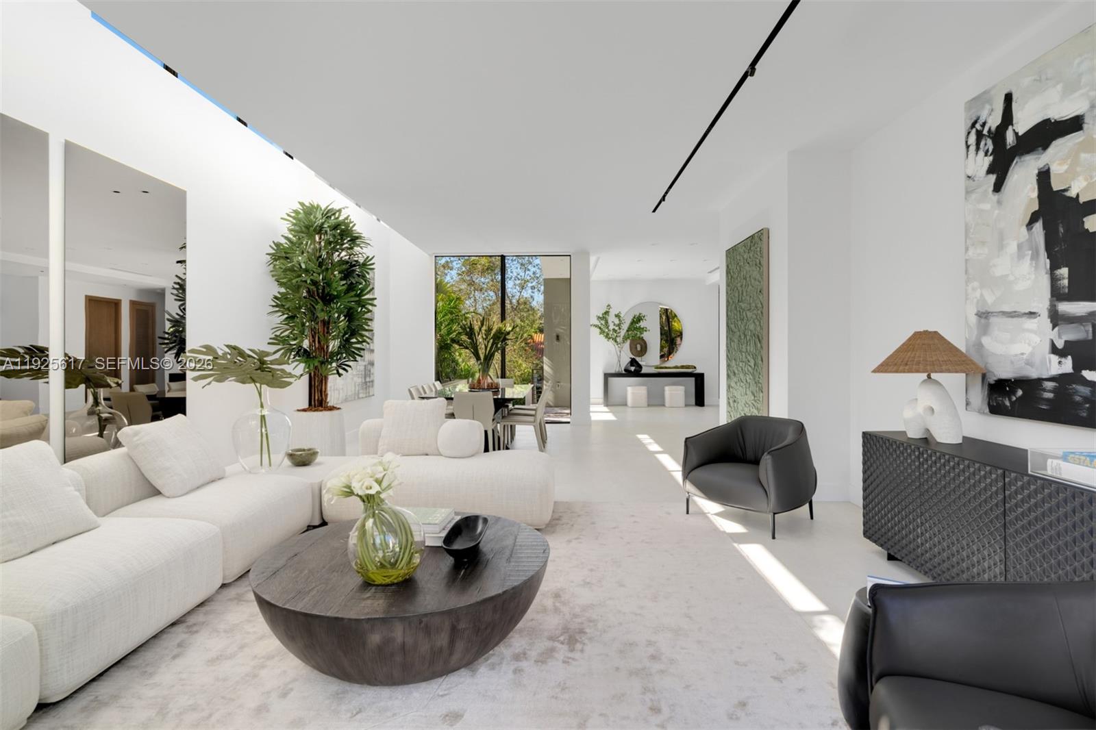 A modern, minimalist living room features white furniture, a dark wood coffee table, and large windows — 3551 Crystal Ct, Miami FL 33133, MIAMI, FL