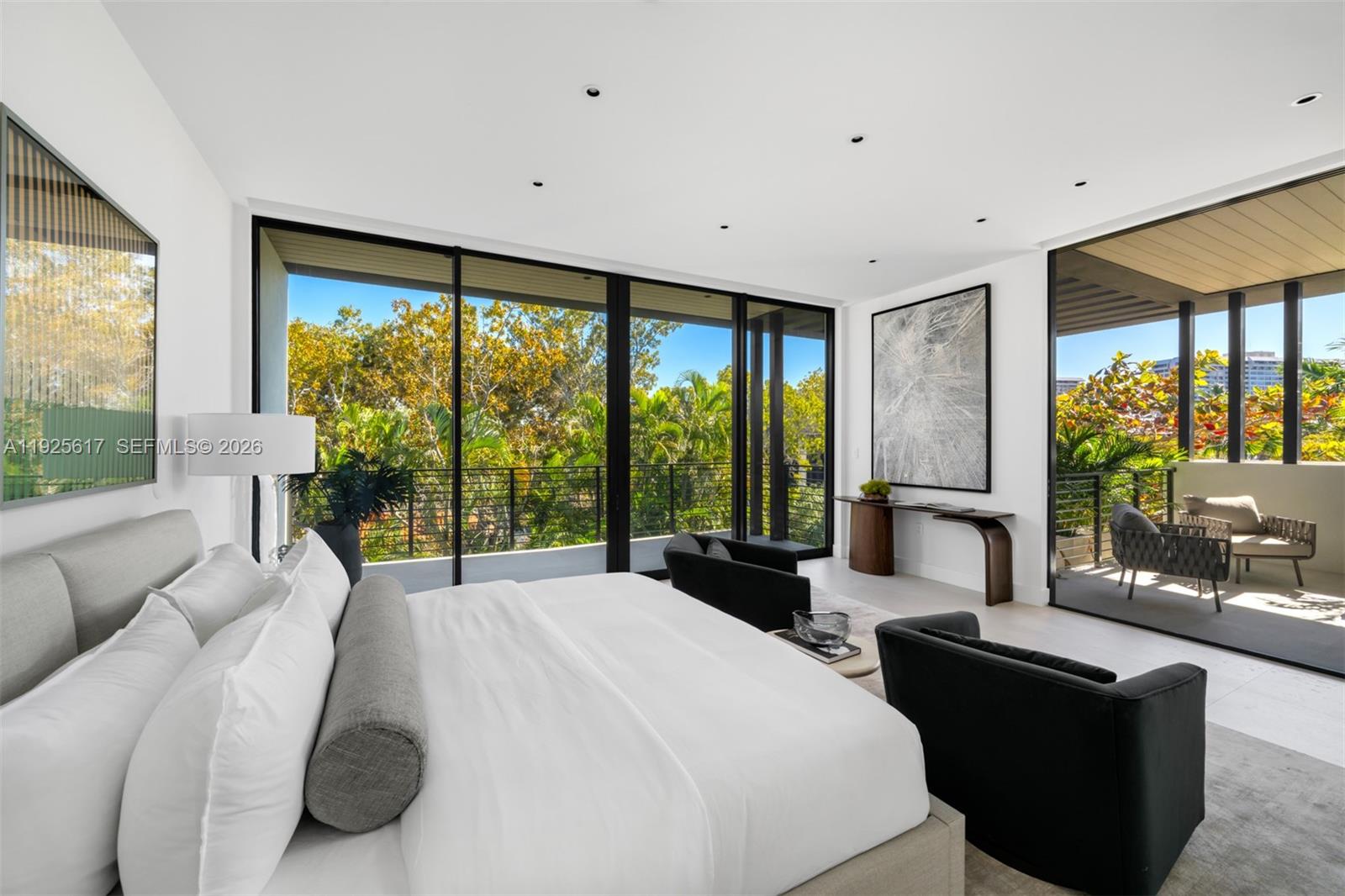 A modern bedroom features a large bed, two black armchairs, and floor-to-ceiling glass doors — 3551 Crystal Ct, Miami FL 33133, MIAMI, FL