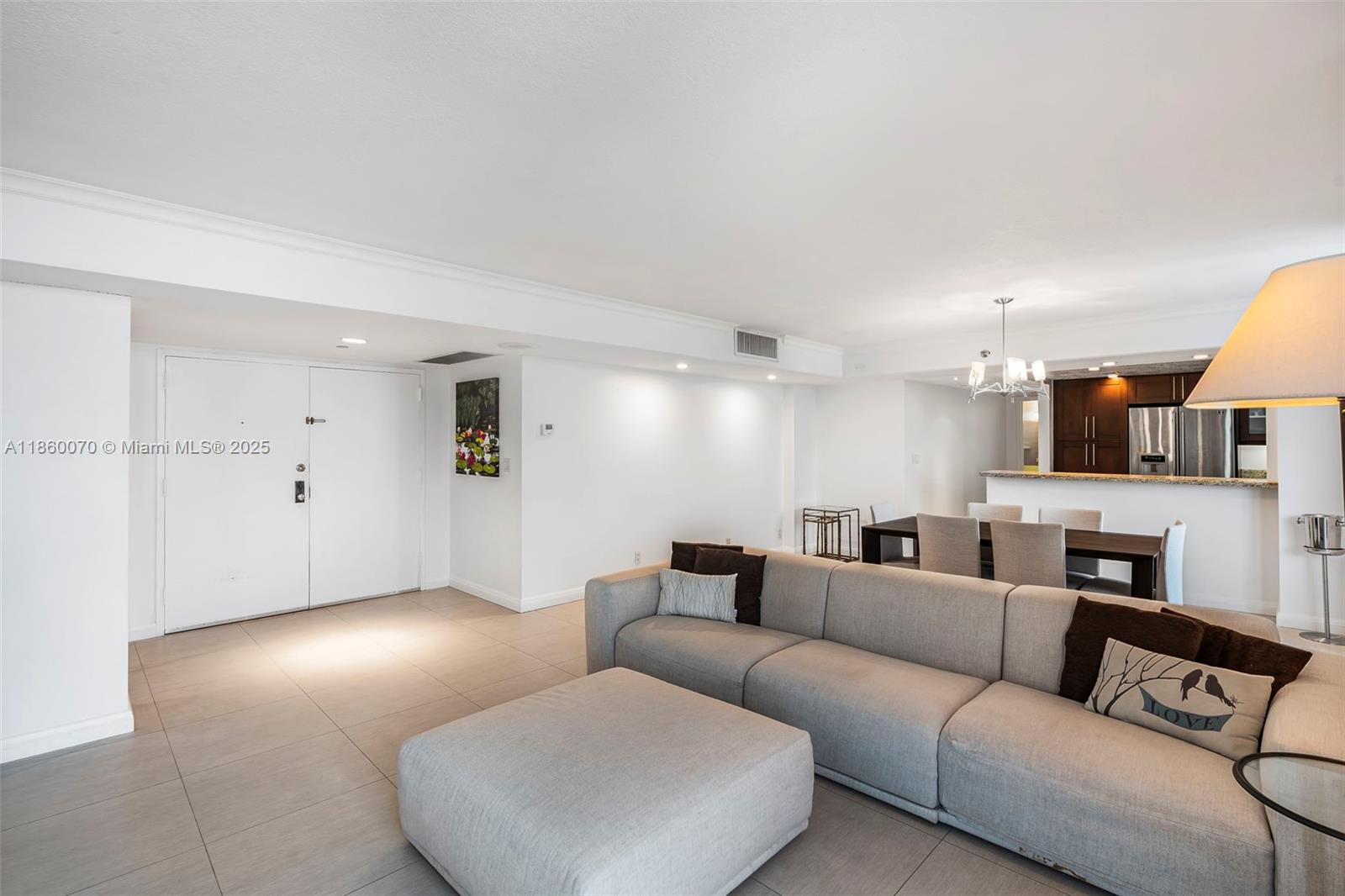 A living room features light tile flooring, a large gray sectional sofa, and an open kitchen — 2401 Collins Ave # 1808, Miami Beach FL 33140, MIAMI BEACH, FL