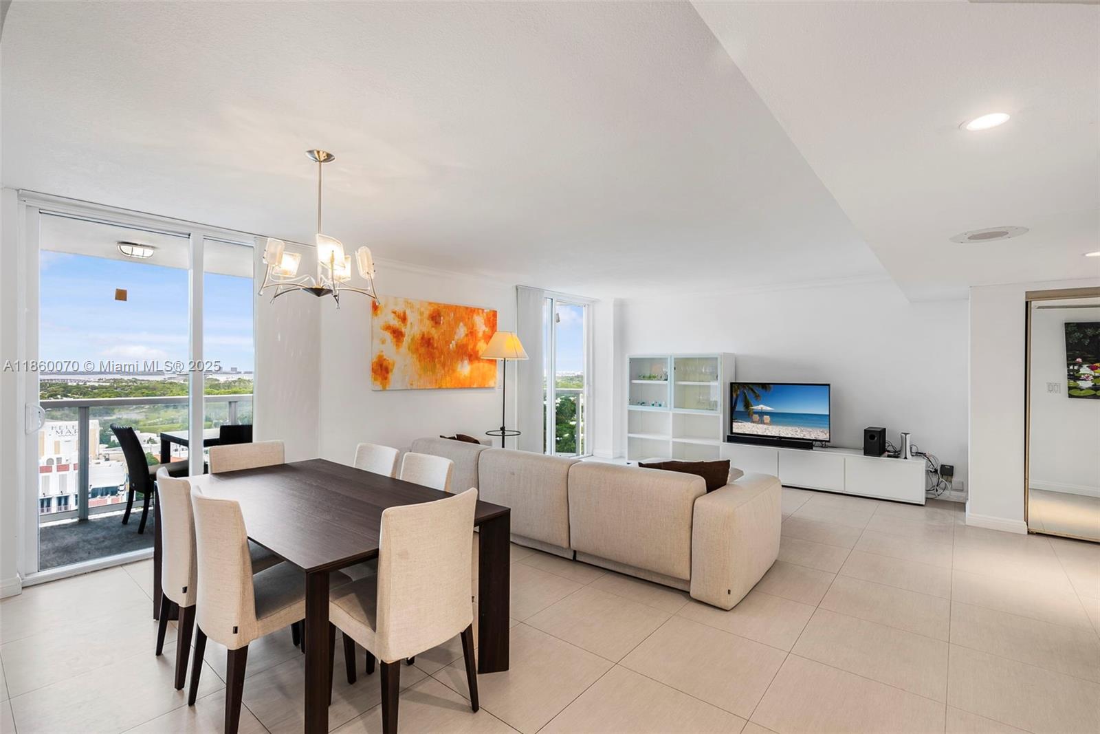 A bright living and dining area features a dark wood table, sectional sofa, and balcony — 2401 Collins Ave # 1808, Miami Beach FL 33140, MIAMI BEACH, FL