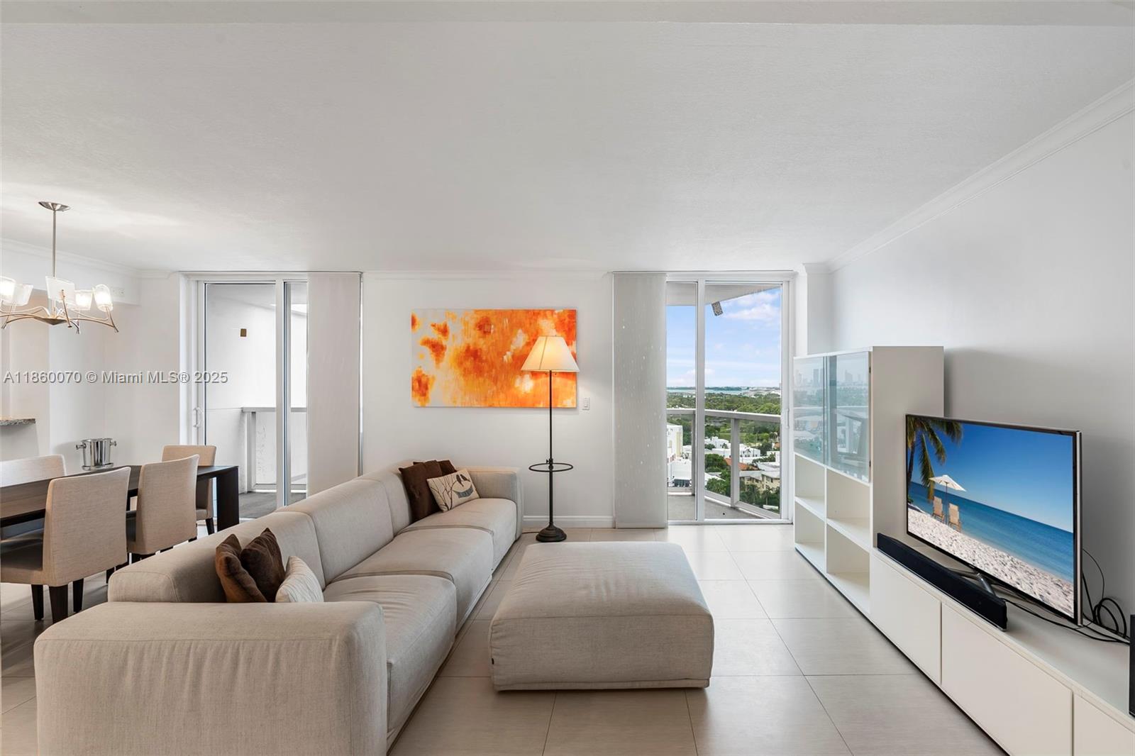 A living room features a beige sofa, a large ottoman, and a view of the outdoors — 2401 Collins Ave # 1808, Miami Beach FL 33140, MIAMI BEACH, FL