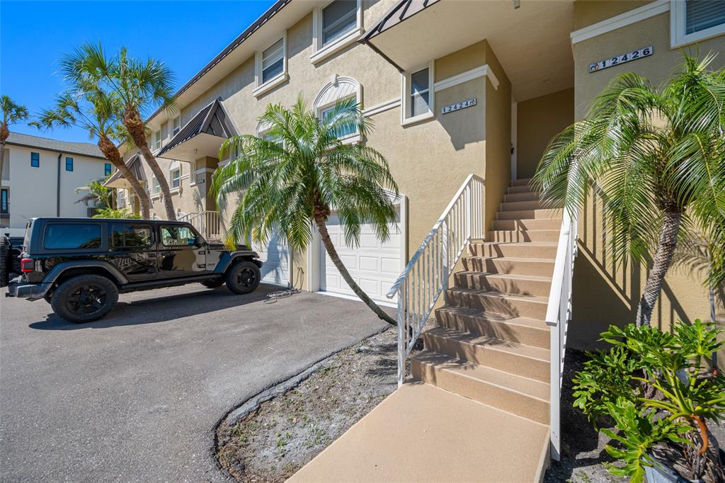 A black Jeep is parked in front of a tan townhouse with exterior stairs — 12424 CAPRI CIRCLE N UNIT 5, TREASURE ISLAND, FL
